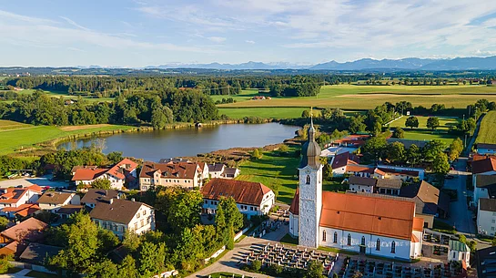 Das Foto zeigt eine Luftaufnahme von Eiselfing mit dem Eiselfinger See im Hintergrund.